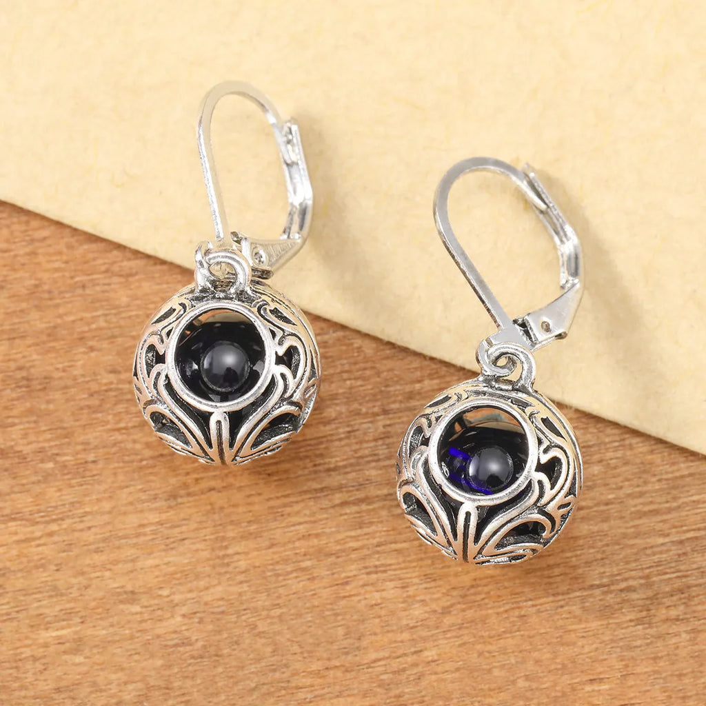 Silver geometric pendant earrings with vintage engraving and hollow design around blue gemstone
