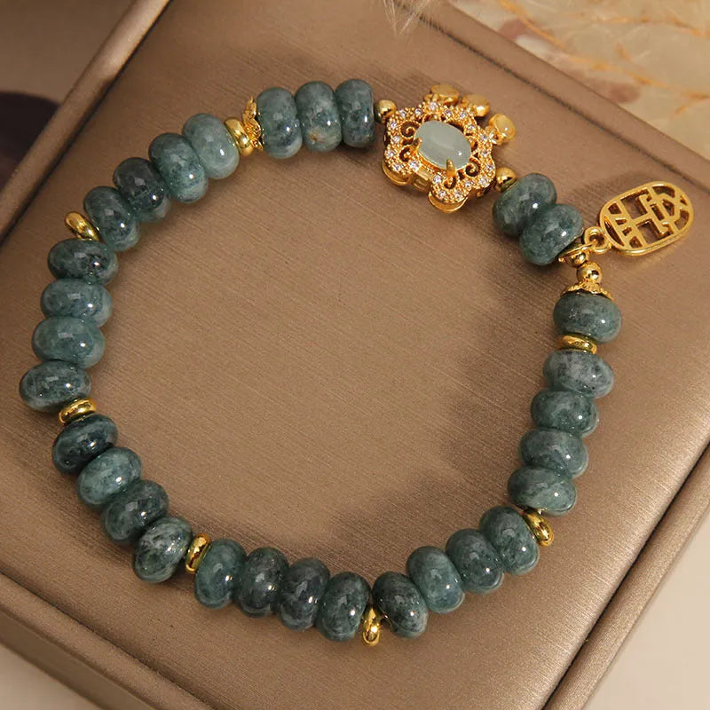 Close-up of a women's bracelet with natural emerald green jade abacus beads and a metallic alloy safety lock clasp.