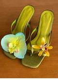 Handmade women's high-heel sandals with square toe and asymmetric floral decoration on calf leather.