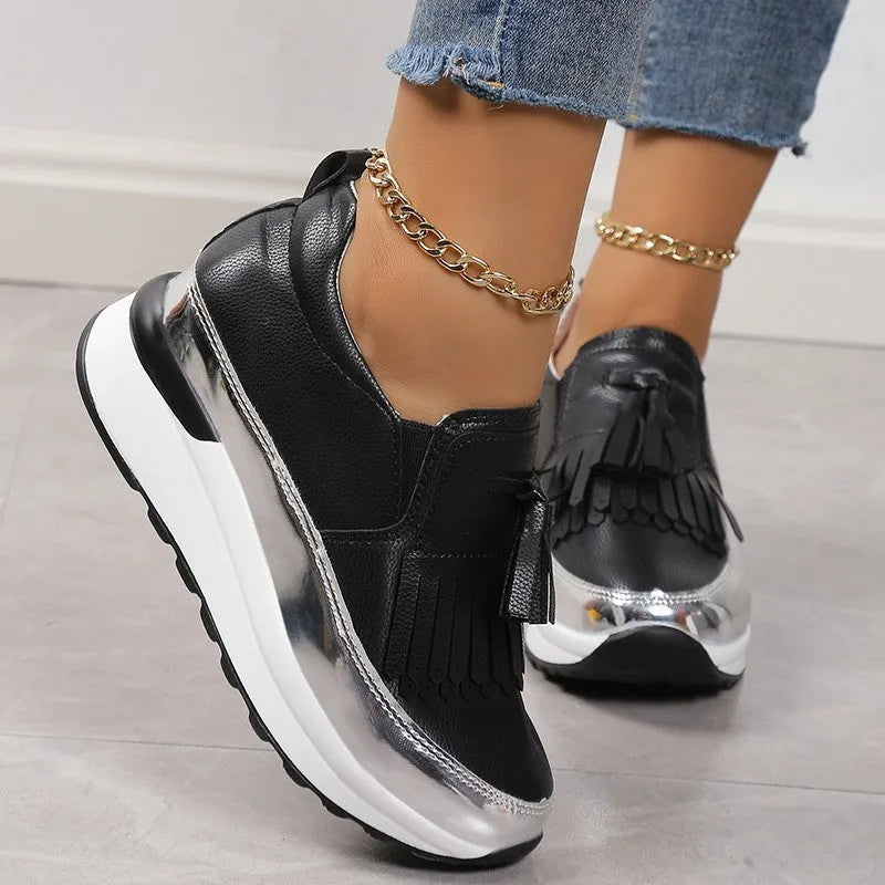 Women's black casual platform shoes with a tassel and muffin wedge heel on a white background.