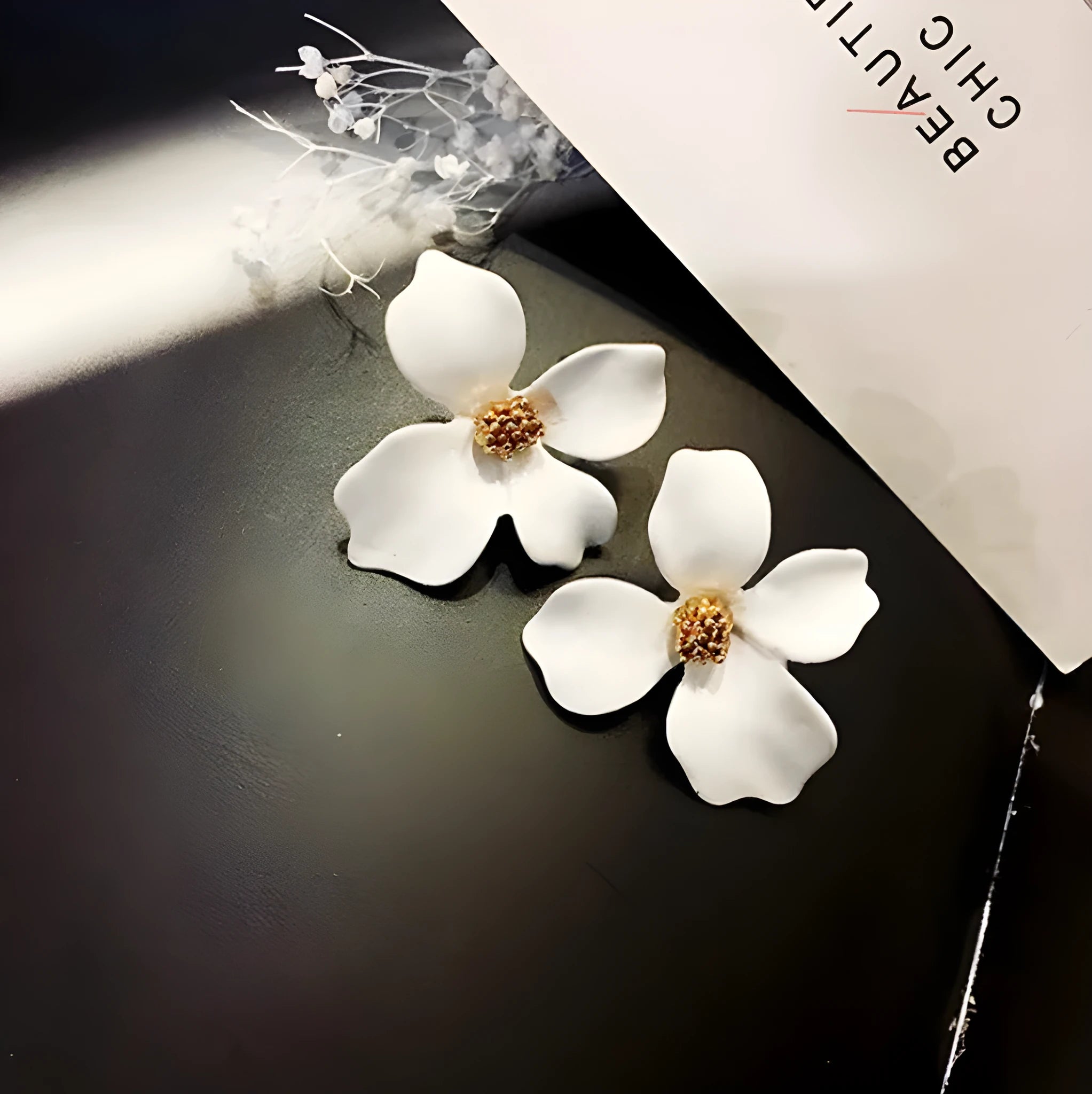 A pair of pink and white flower-shaped stud earrings with butterfly backs on a white background.