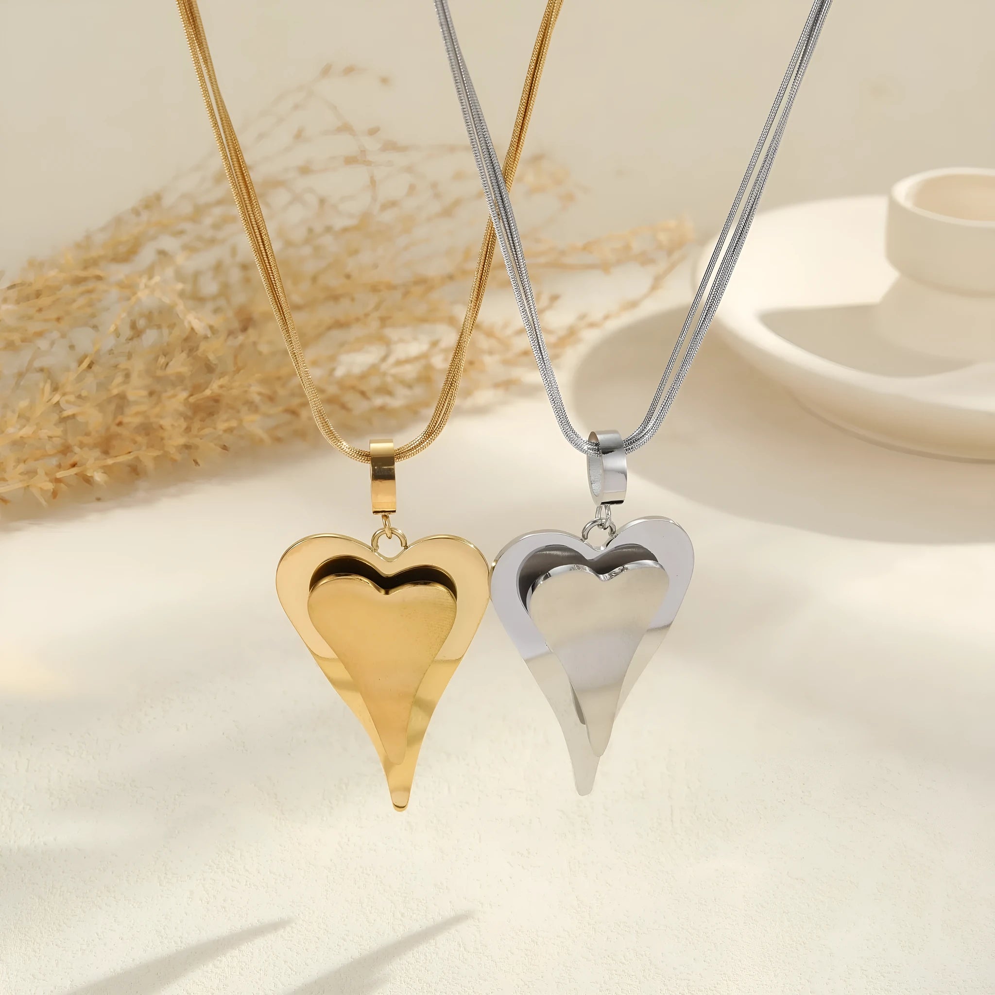 Geometric double heart pendant on a stainless steel snake bones chain necklace in gold or steel finish.