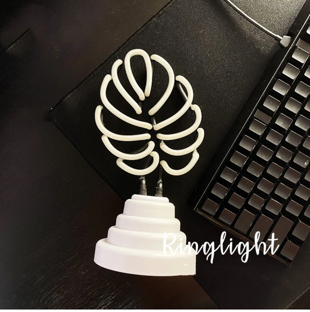 White bamboo-shaped desktop lamp with green light, USB cable, and minimalist design on wooden desk