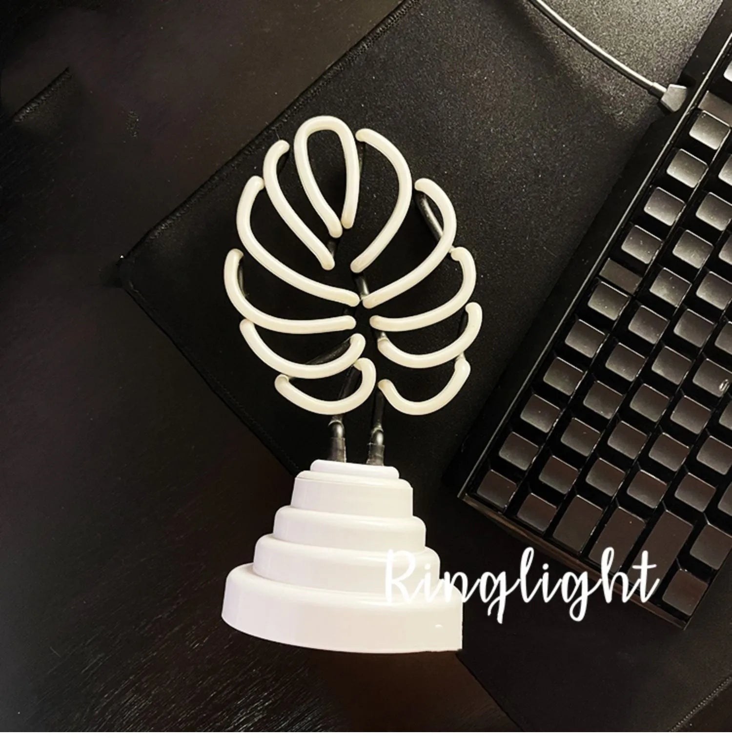 White bamboo-shaped desktop lamp with green light, USB cable, and minimalist design on wooden desk