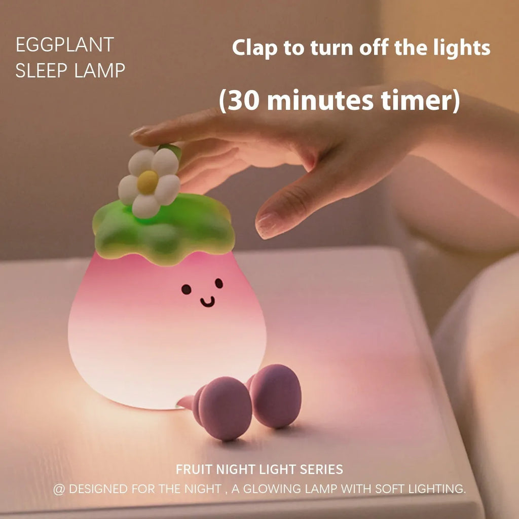 Cartoon-shaped eggplant night lamp glowing with soft yellow light on a table.