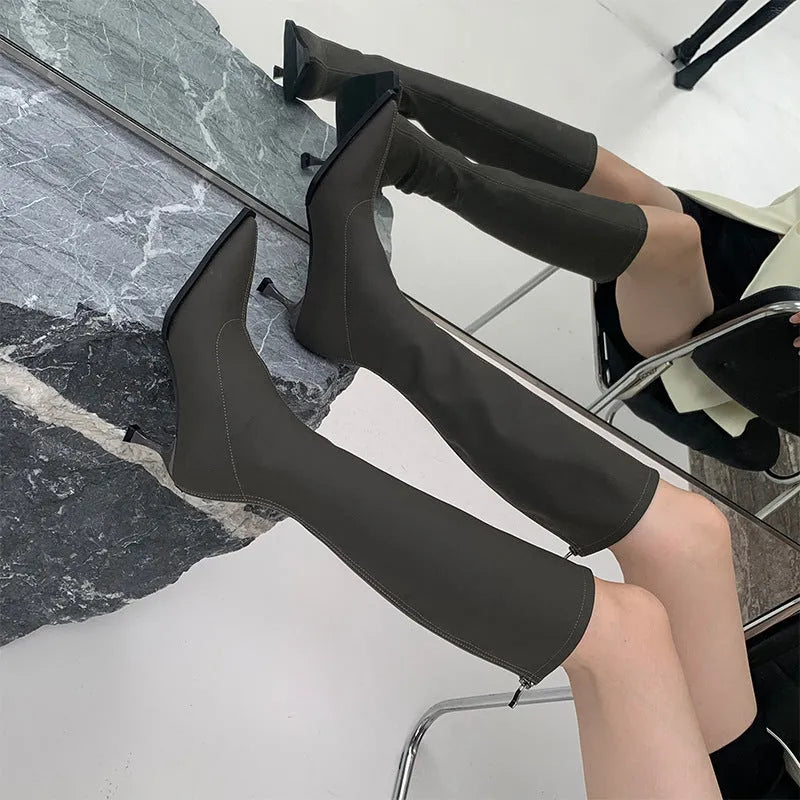 Women's black below the knee boots with pointed toe, 5cm stiletto heel, and back zipper on a solid background.
