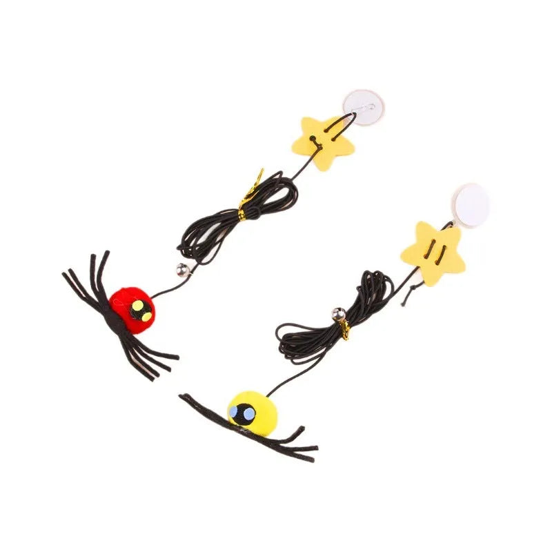 Red and yellow elastic rope cat toy hanging from a door, with feathers, a plastic spider, and a bell.