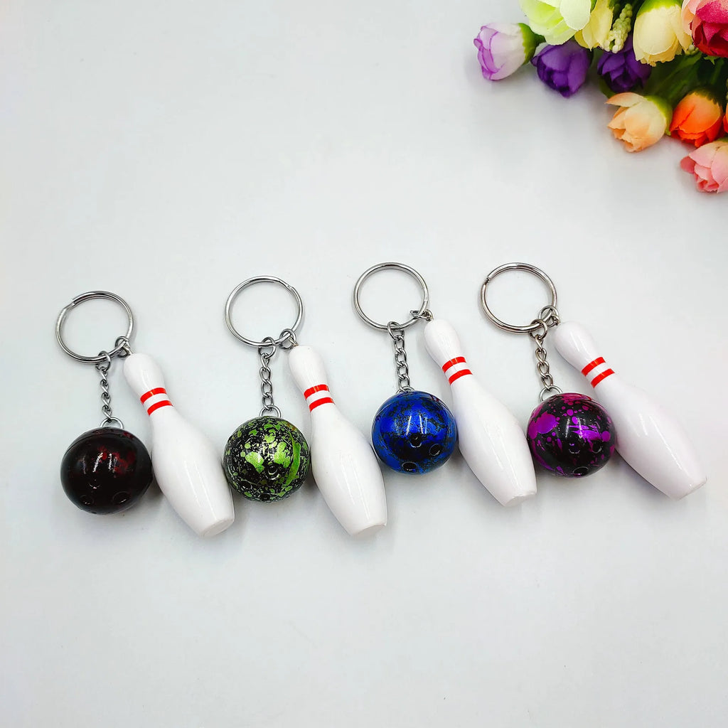 Mini bowling pin keychain pendant in four colours: dark red, blue, purple, green, showing PVC metal construction