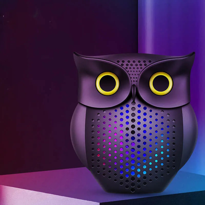 Black plastic owl-shaped portable Bluetooth speaker on a table.