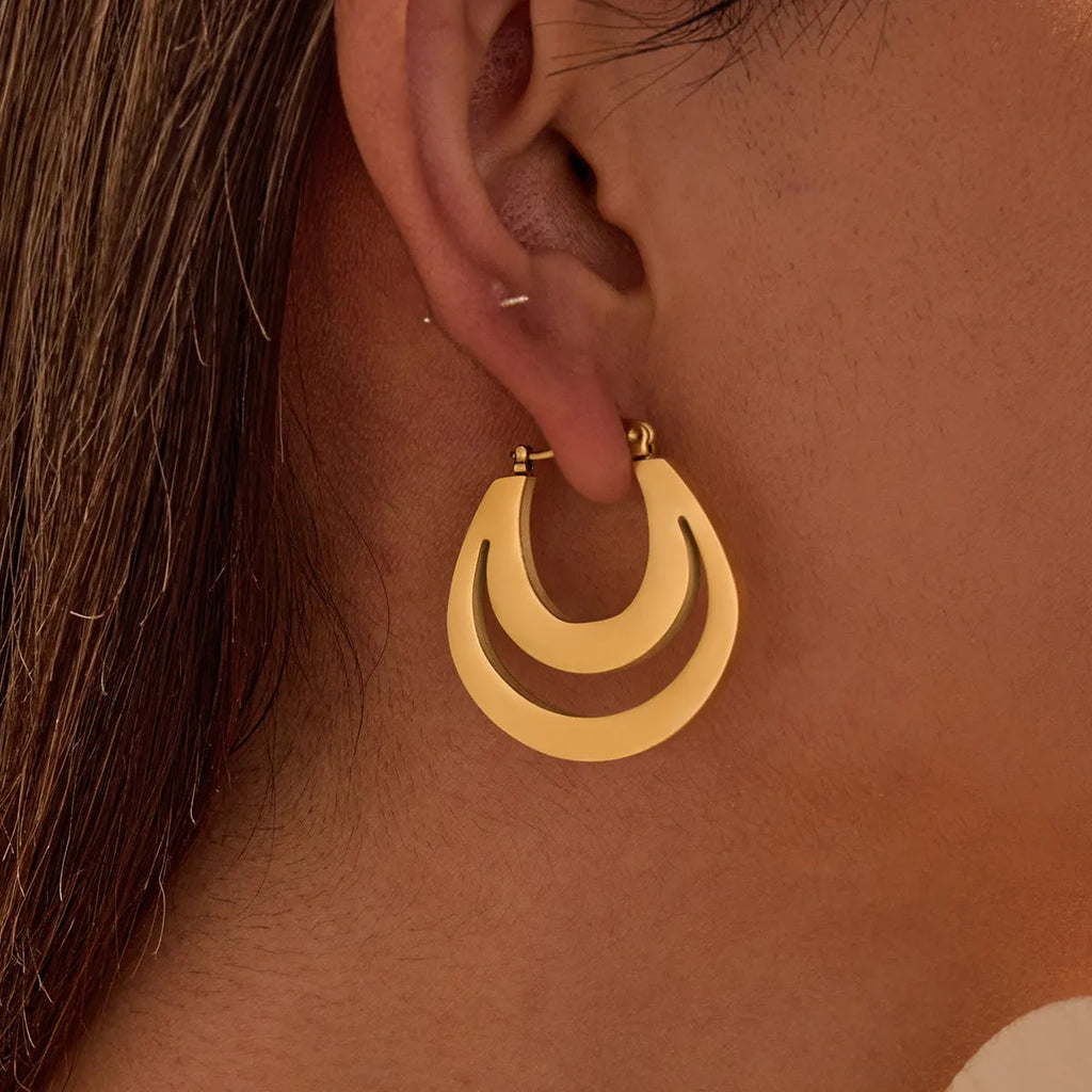 A pair of geometric minimalist French earrings in a round ring design, shown in both gold and steel metallic finishes.