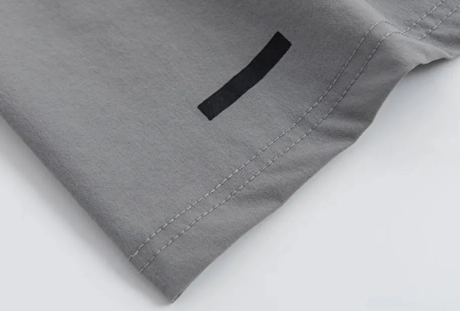 Loose fit grey sports cropped pants with a printed elastic waistband, shown on a model.