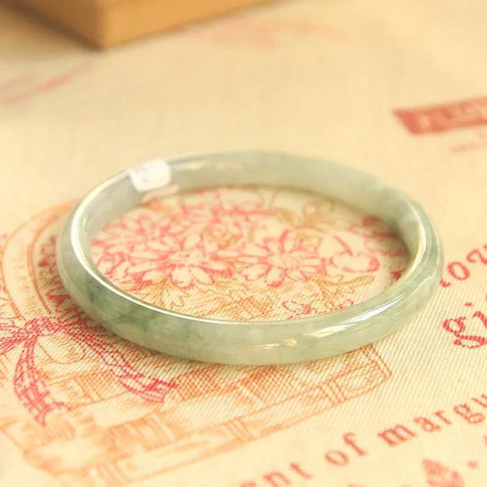 Green jade waxy geometric bracelet with Chinese design elements on wrist