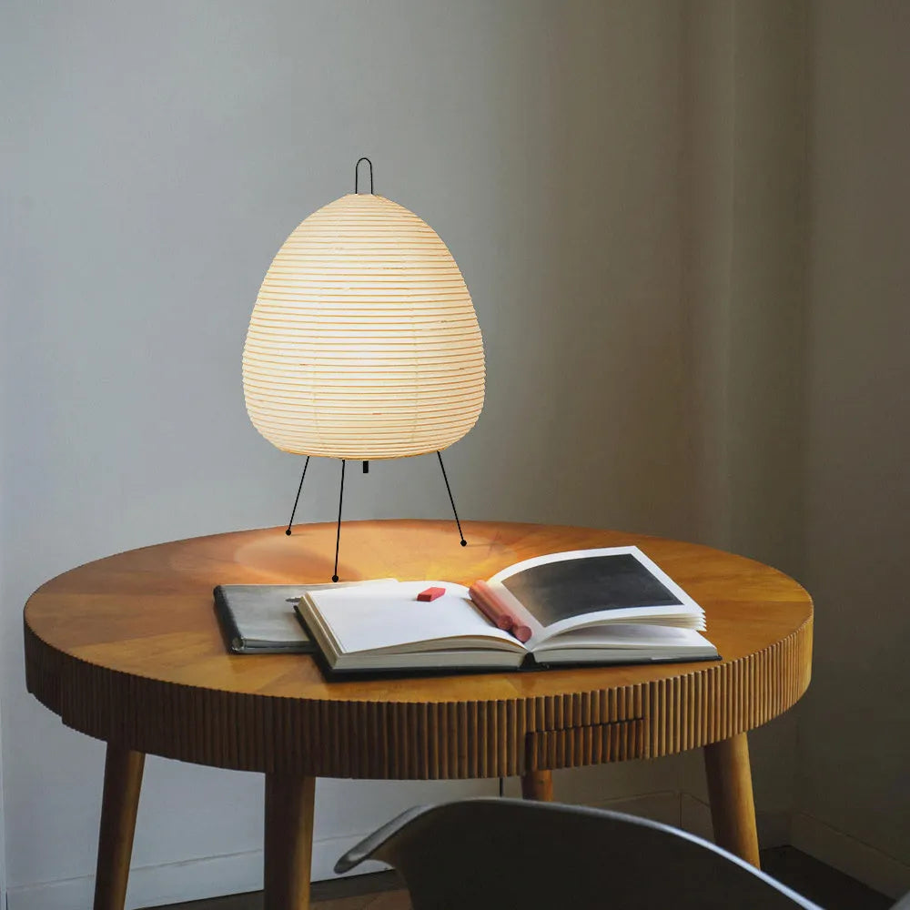 Japanese style rice paper table lamp with aluminium base on a wooden surface.