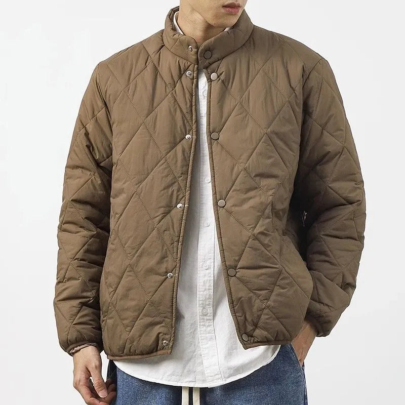 Man wearing a long black diamond quilted padded winter jacket with a loose fit.