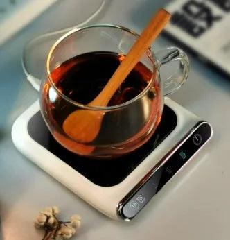 Black USB-powered cup warmer heating coaster with control buttons on a desk next to a coffee mug.