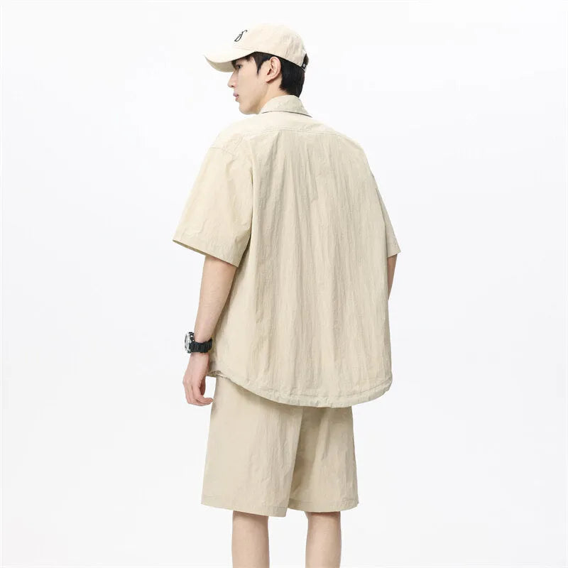 Man wearing a dark grey shirt and matching loose shorts from a men's casual two-piece set.