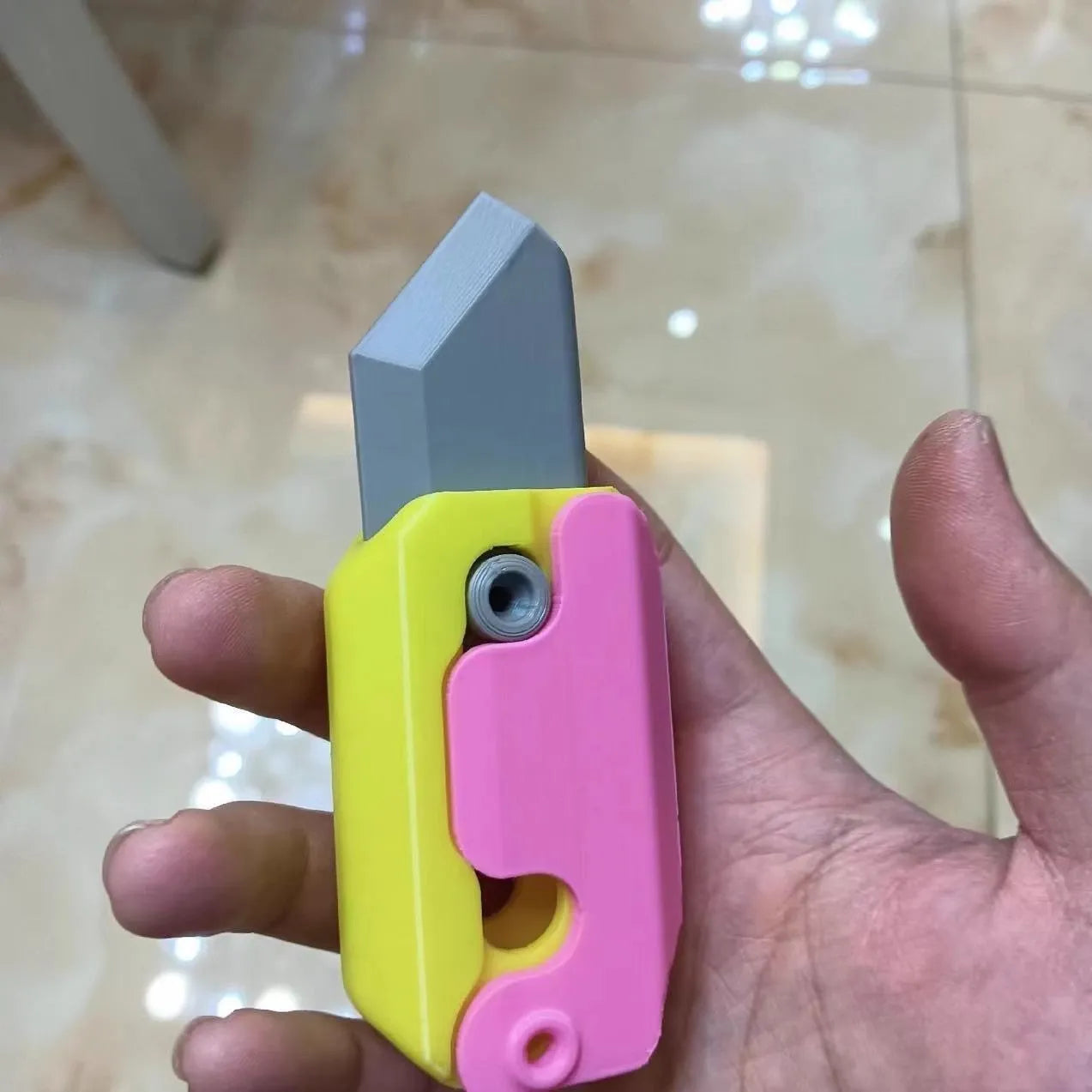3D printed orange and green carrot-shaped gravity flick knife fidget toy on a white background.
