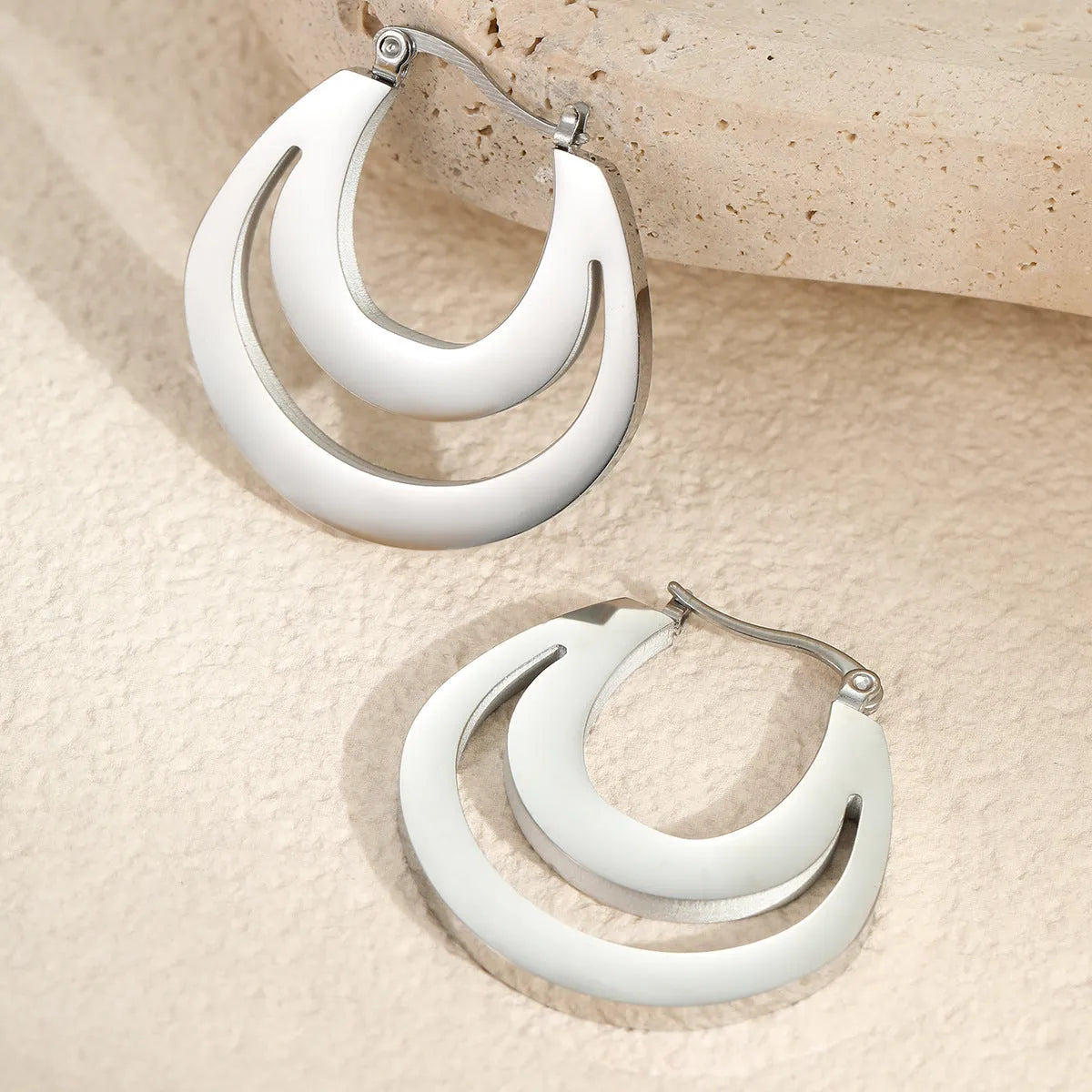A pair of geometric minimalist French earrings in a round ring design, shown in both gold and steel metallic finishes.