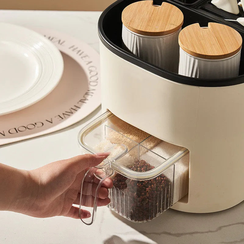 White rotating kitchen storage bucket with utensils next to a four-compartment spice box on a countertop.
