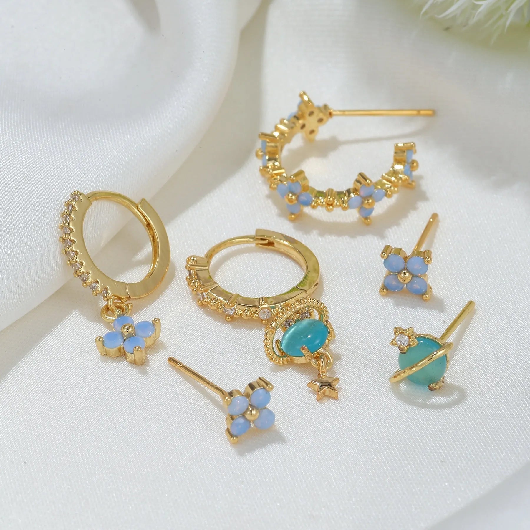 Flower-shaped ear studs with zircon mosaic in gold or silver finish, showing geometric design details