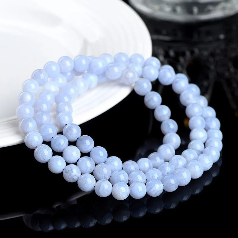 Blue agate bracelet with 6-6.8mm beads showing multi-circle pattern and scattered striped agate beads, Ruyi elements visible