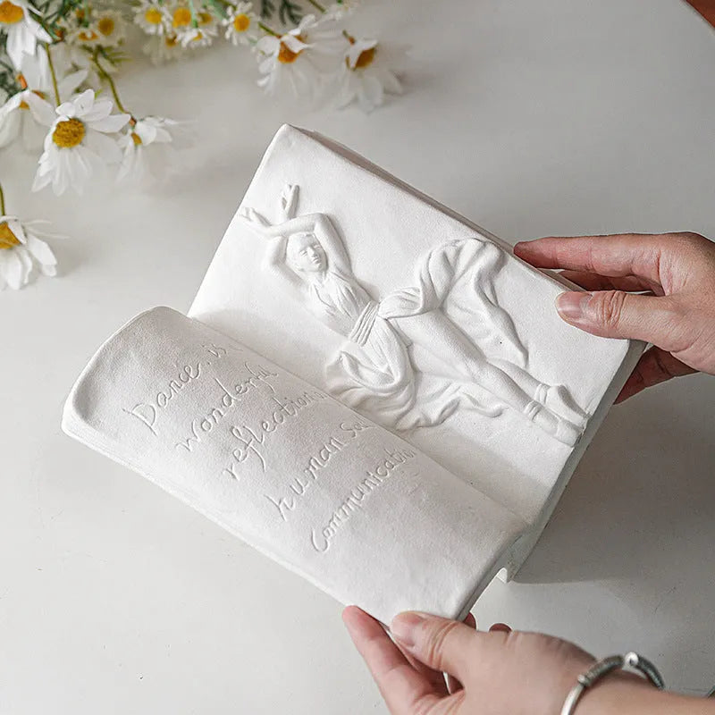 Ceramic book stand in lover design with glazed surface, approximately 15cm tall, on a wooden desk