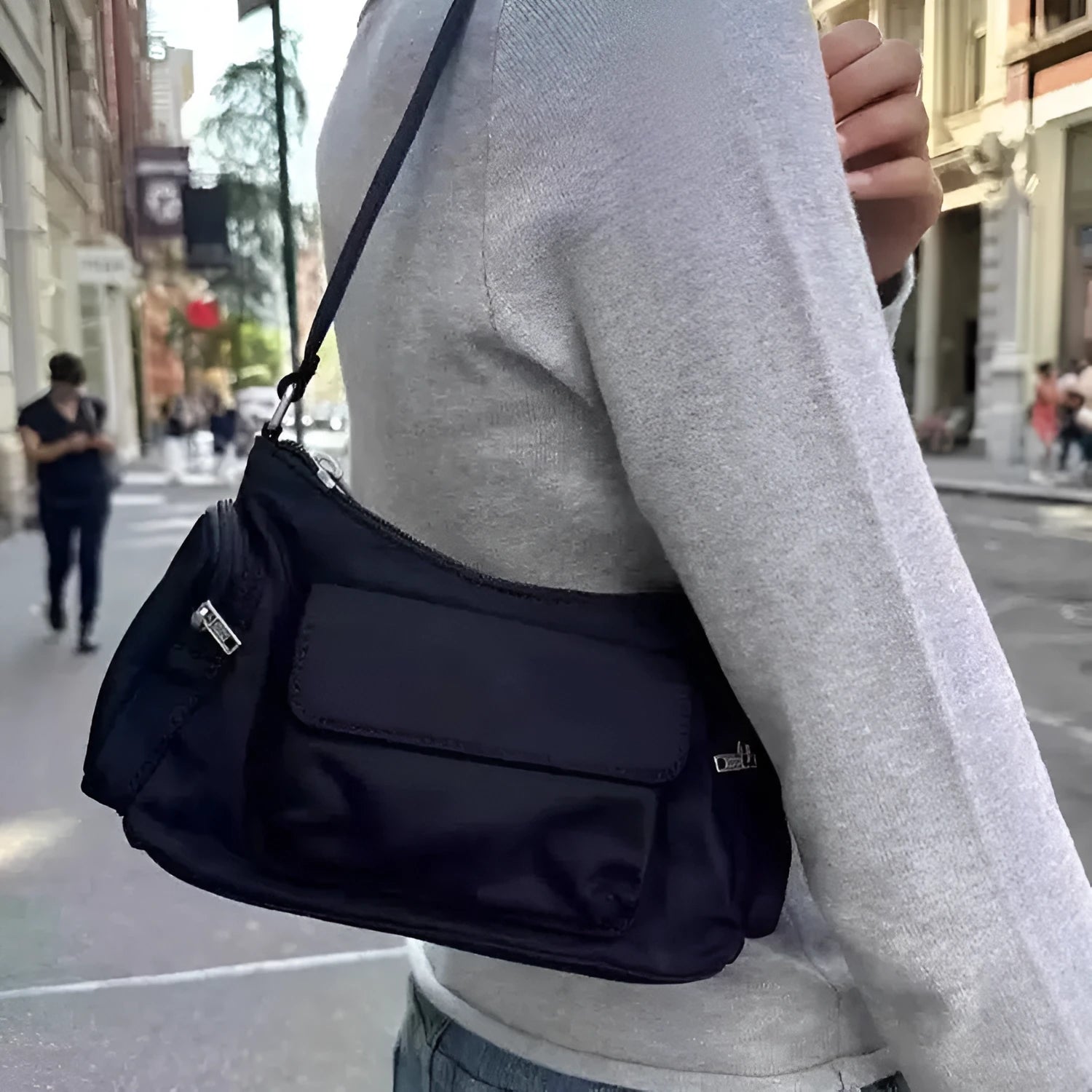 Black shoulder bag with two pockets showing side line detailing, measuring 24cm long by 9cm wide