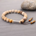 Handmade natural stone bead bracelet in a wood tone colour on a white background.