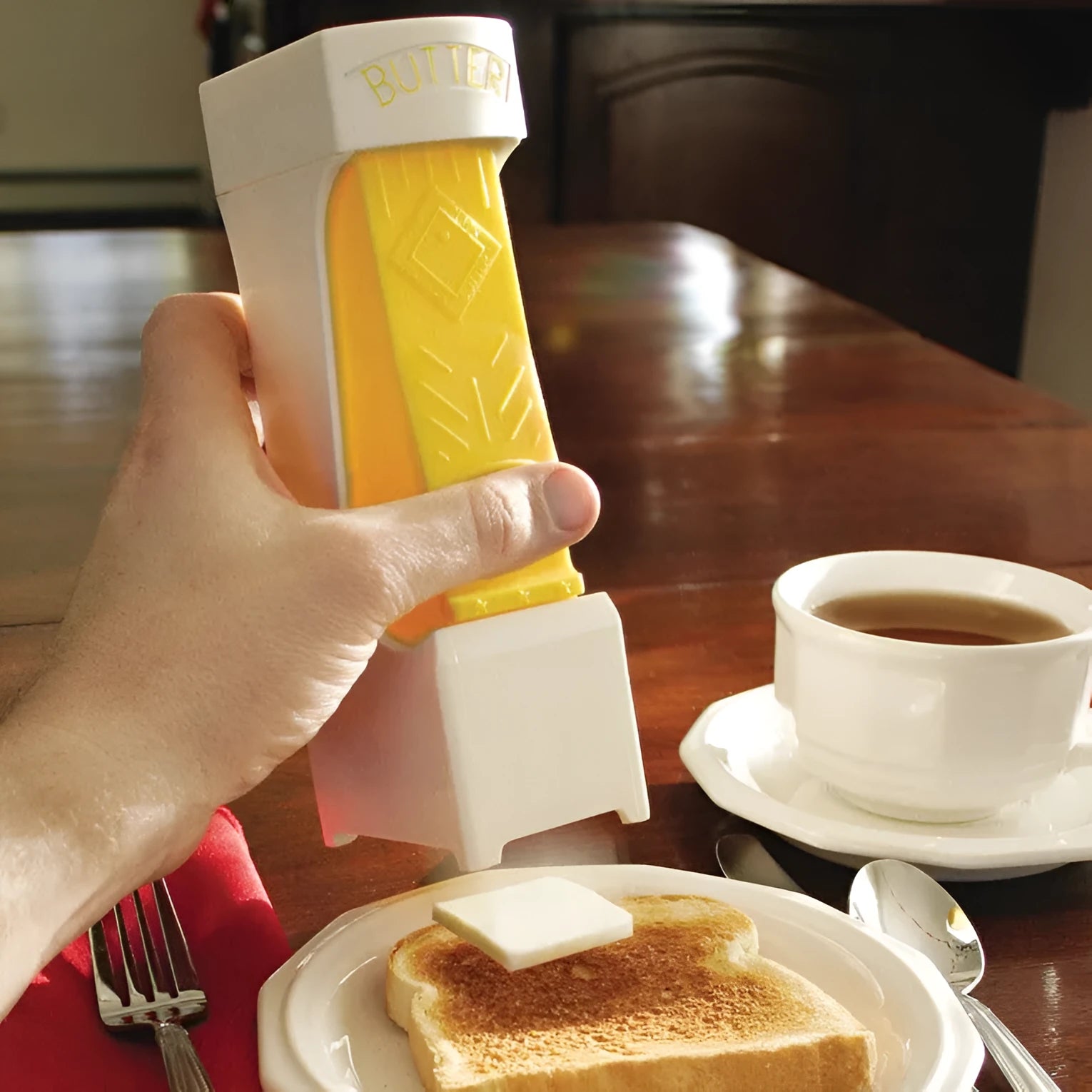 Yellow plastic butter slicer and storage box with a one-button dispenser for standard 4.75 inch butter bars.