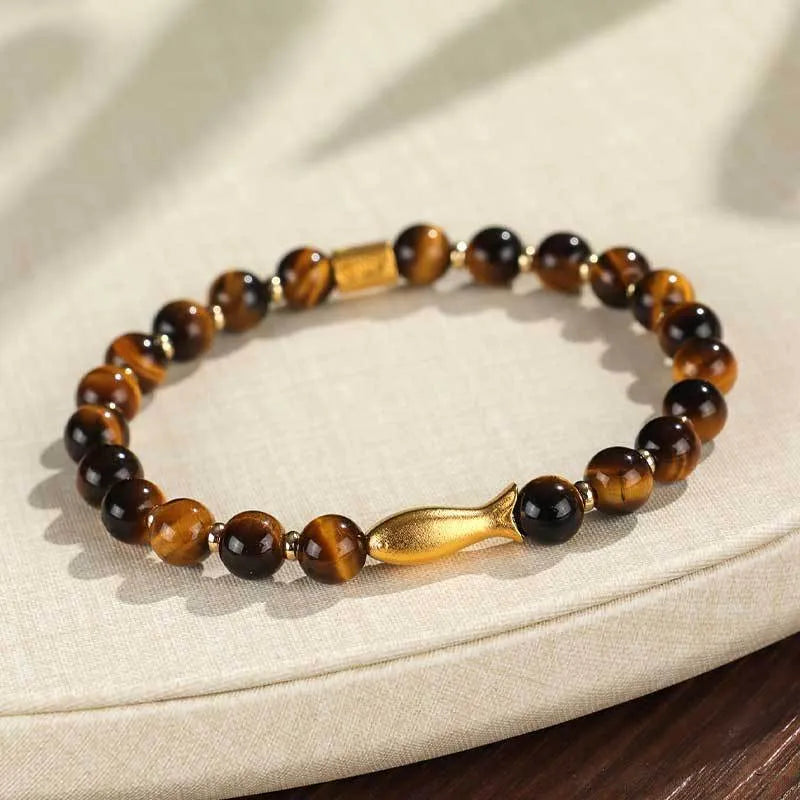 Yellow tiger eye bracelet with small fish bead charm on woman's wrist