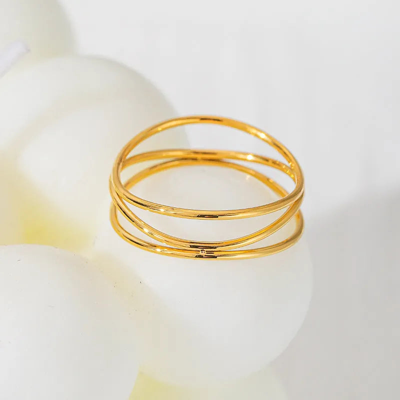 Gold-coloured geometric line ring with a three-layer coil design on a titanium steel band.