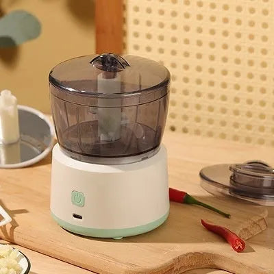 Mini meat grinder with white or light green housing, stainless steel blades, and transparent 225ml cup on anti-slip pad