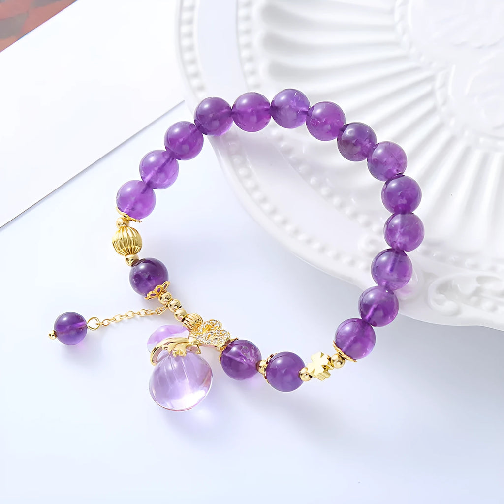 Purple amethyst bracelet with detailed money bag charm and peace buckle pendant on wrist