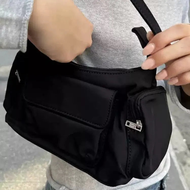 Black shoulder bag with two pockets showing side line detailing, measuring 24cm long by 9cm wide