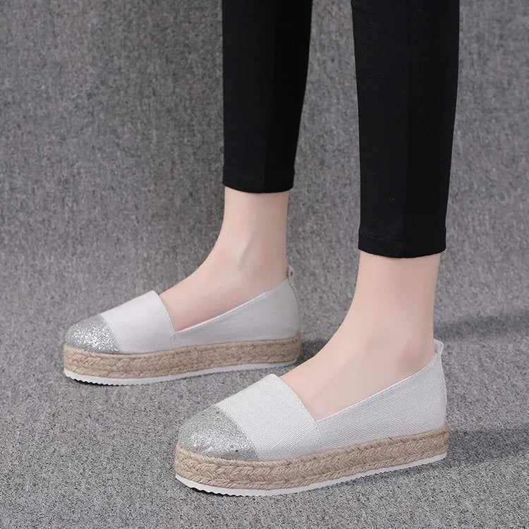 Beige and black canvas shoe covers with round toe design showing oversleeves construction