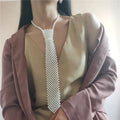 Close-up of a white imitation pearl body chain with an adjustable alloy tie clasp on a dark background.