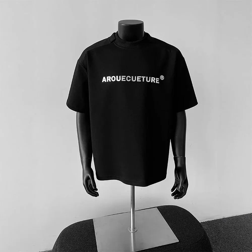 Men's short-sleeve cotton pullover in light grey with letter pattern, showing loose fit and regular sleeves.