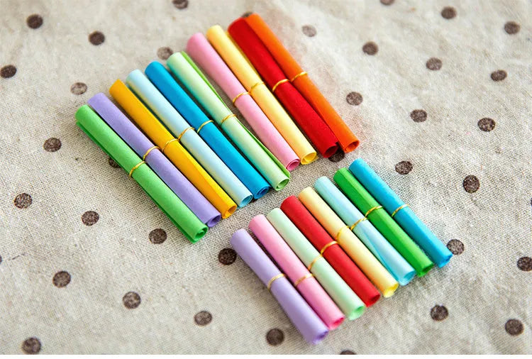 Assorted colourful mini paper scrolls with eyelets for drift bottle messages in sizes 3x7cm, 4x7cm, 7x7cm, and 5x5cm.
