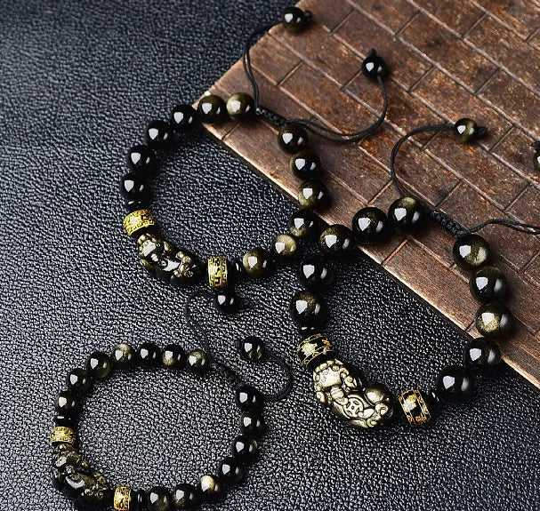 Hand-woven Golden Obsidian Pi Xiu bracelet with animal charm on wrist, showing bead detail.