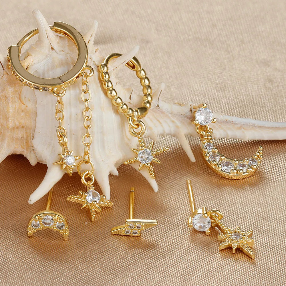 XINGX set of six gold chain tassel and zircon stud drop earrings laid out on a dark surface
