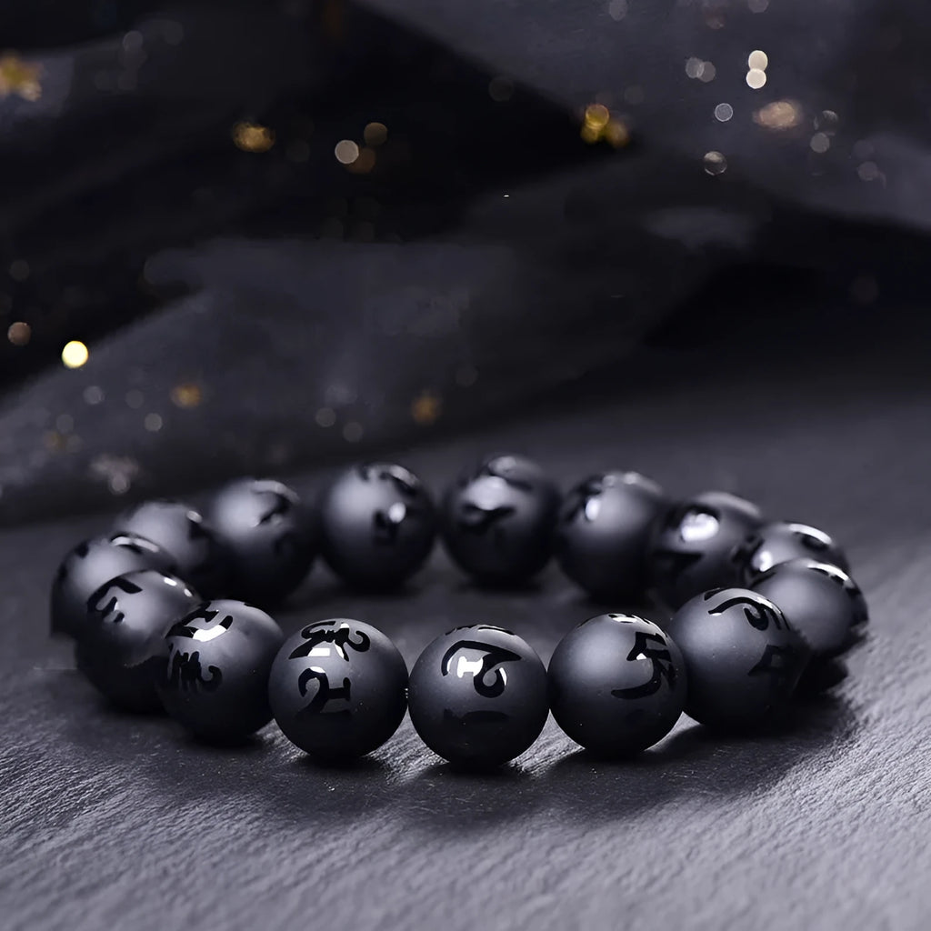 Natural frosted black agate bracelet with Sanskrit mantra and auspicious patterns, showing matte black stone glaze.
