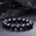 Natural frosted black agate bracelet with Sanskrit mantra and auspicious patterns, showing matte black stone glaze.
