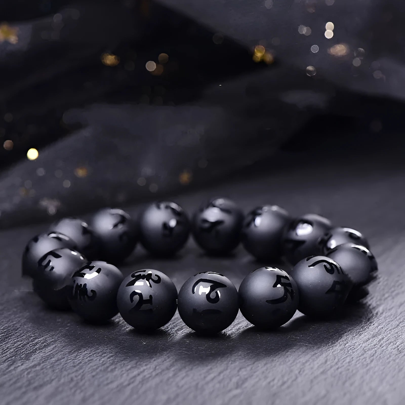 Natural frosted black agate bracelet with Sanskrit mantra and auspicious patterns, showing matte black stone glaze.