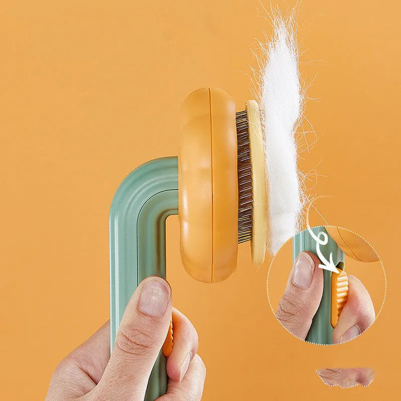 Pumpkin coloured hand-held pet grooming brush with stainless steel needles on a curved comb.