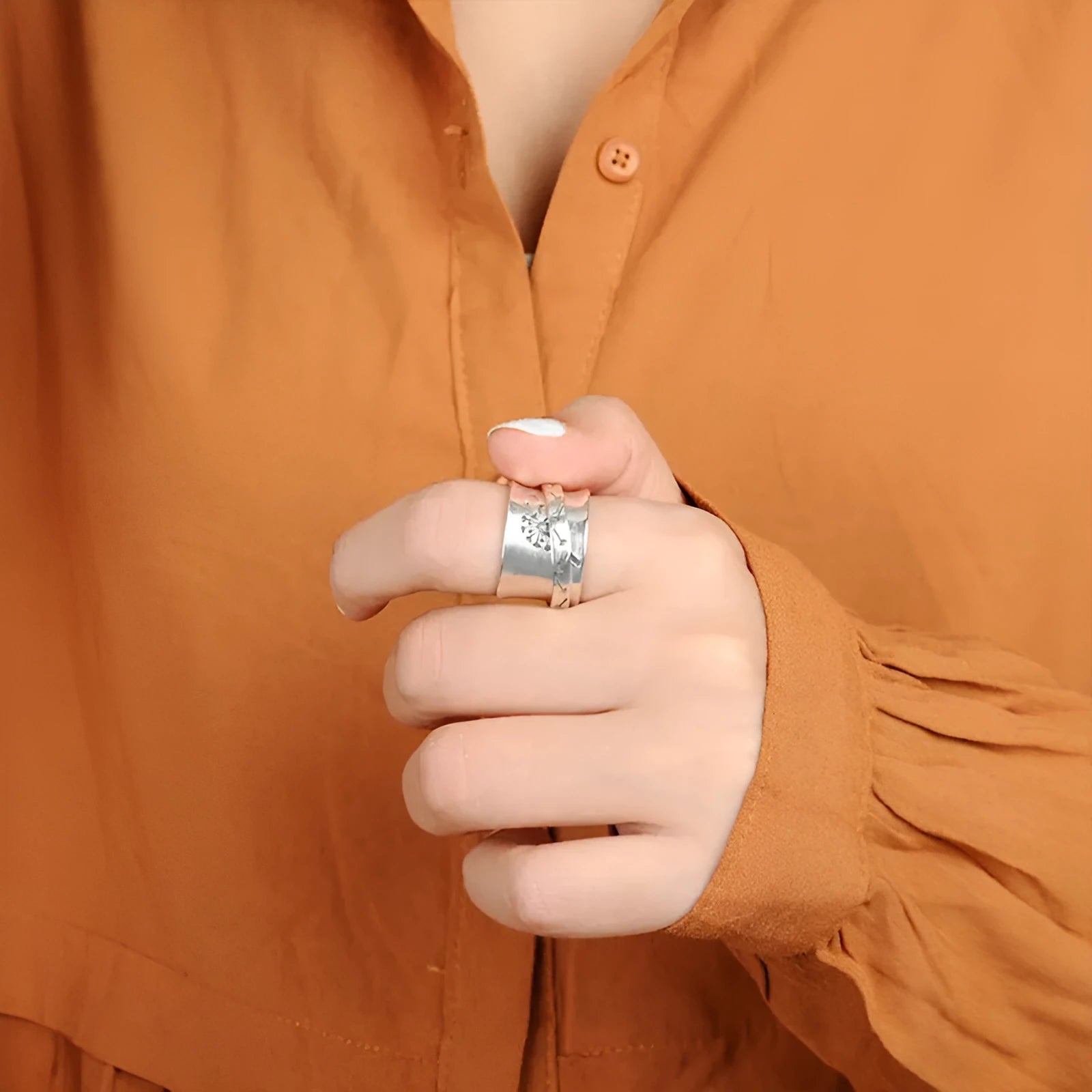Silver flower ring on a finger showing its rotatable band and adjustable open design.