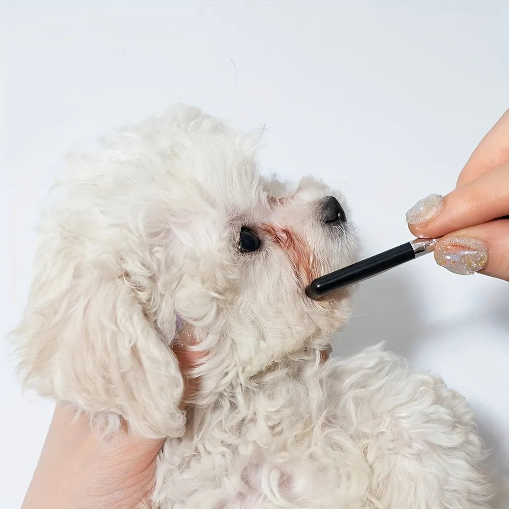 Black ambidextrous pet grooming brush with soft bristles for tear stains and a comb end for hair removal.