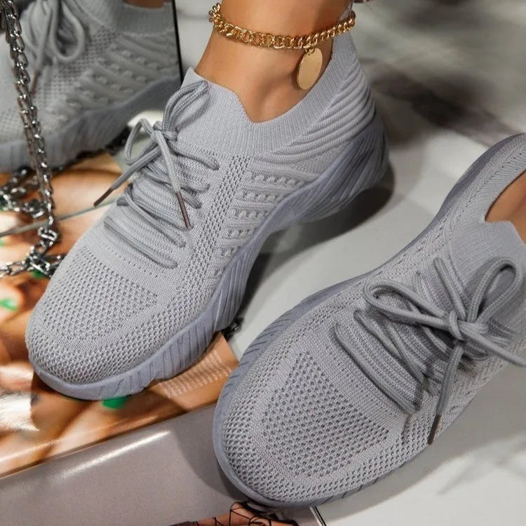 Women's white thick-sole dad sneakers on a plain background, showing the chunky sports shoe design.