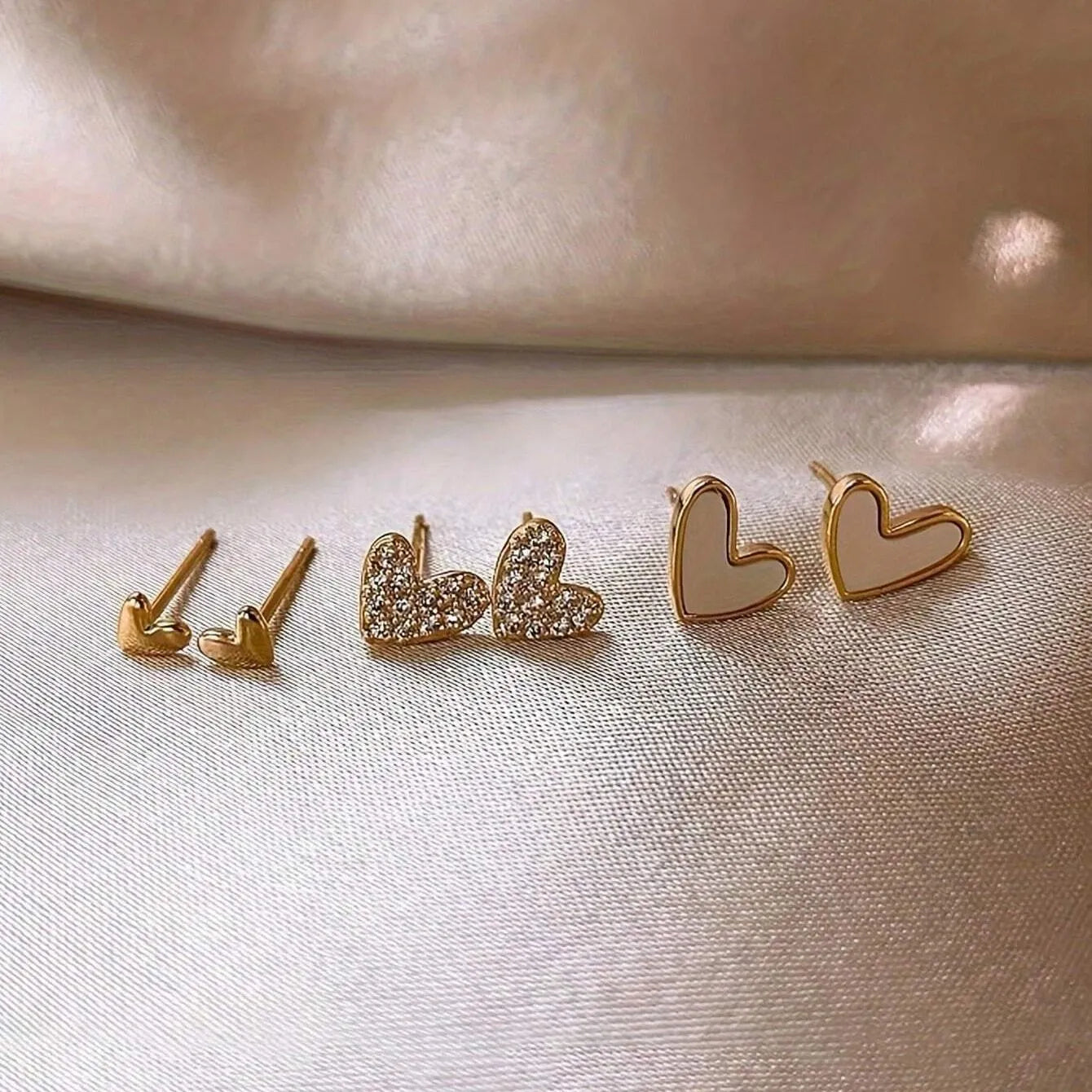 Three pairs of heart-shaped alloy earrings with electroplating in gold, black, black-white, and pink colours