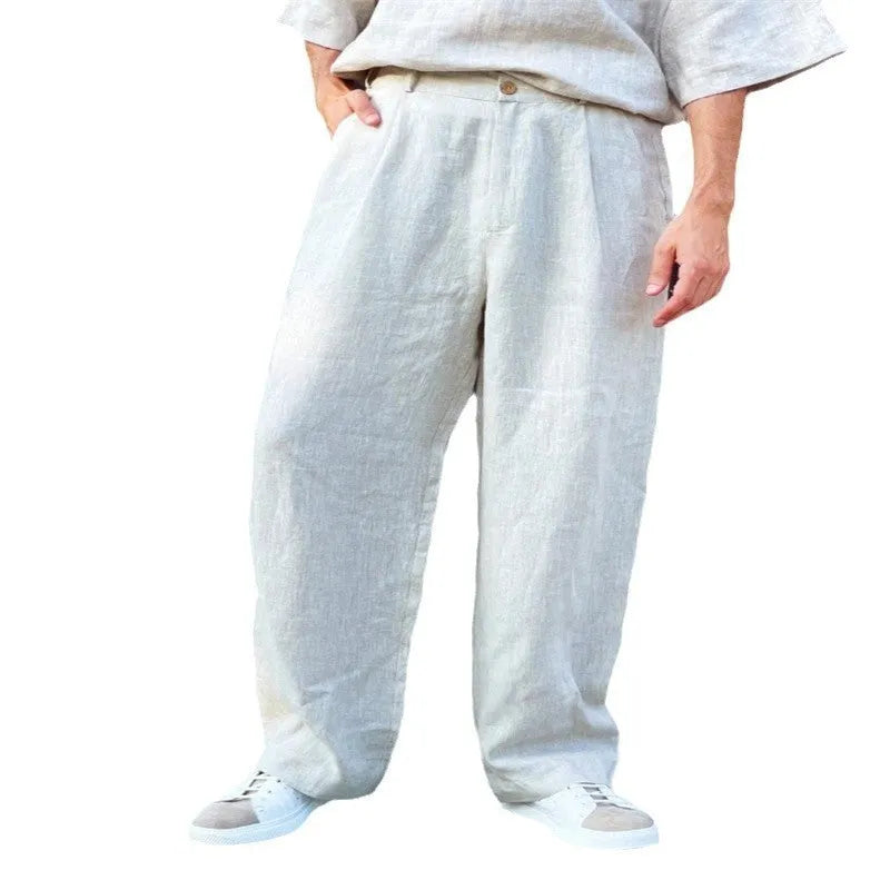Men's loose high-waisted linen pleated jogger pants in a neutral colour on a hanger.