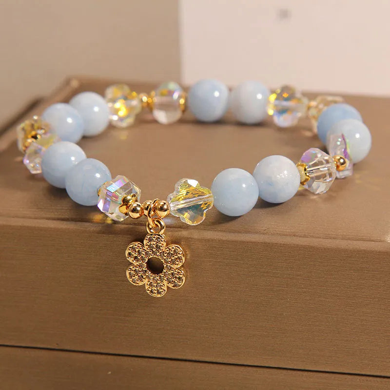 Aquamarine crystal and pearl bracelet with four-leaf clover charm on wrist.